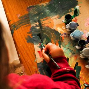 A child creatively paints with various colors indoors, fostering imagination.